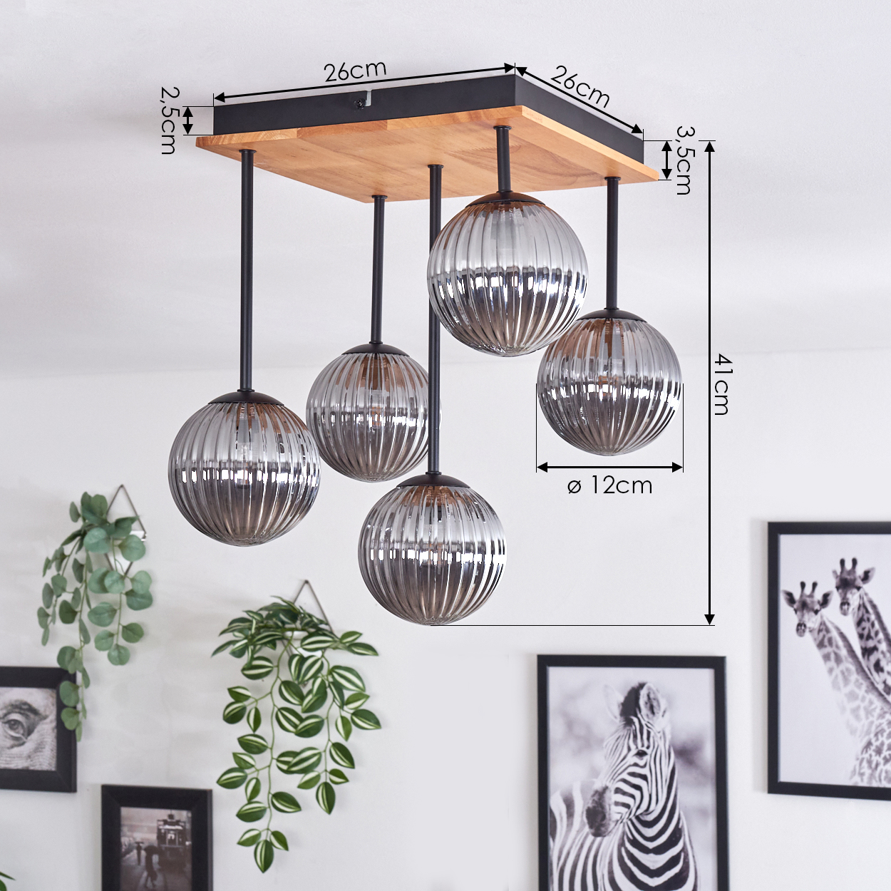 Deckenlampe mit fünf Glaskugeln, Holzsockel. Dekorative Pflanzen und gerahmte Zebra- und Giraffenbilder an der weißen Wand.