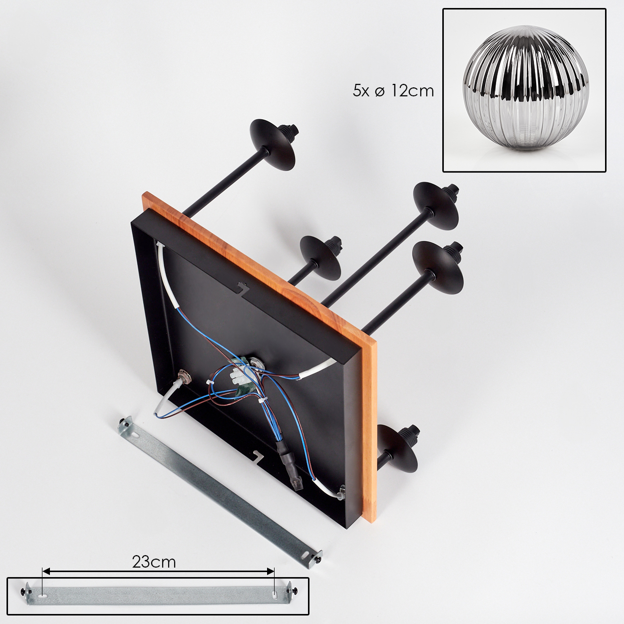Eine zerlegte Leuchte. Sie hat einen schwarzen quadratischen Rahmen mit Holzkanten, schwarze Stiele und eine Metallkugel. Darunter liegt ein Metallstab.