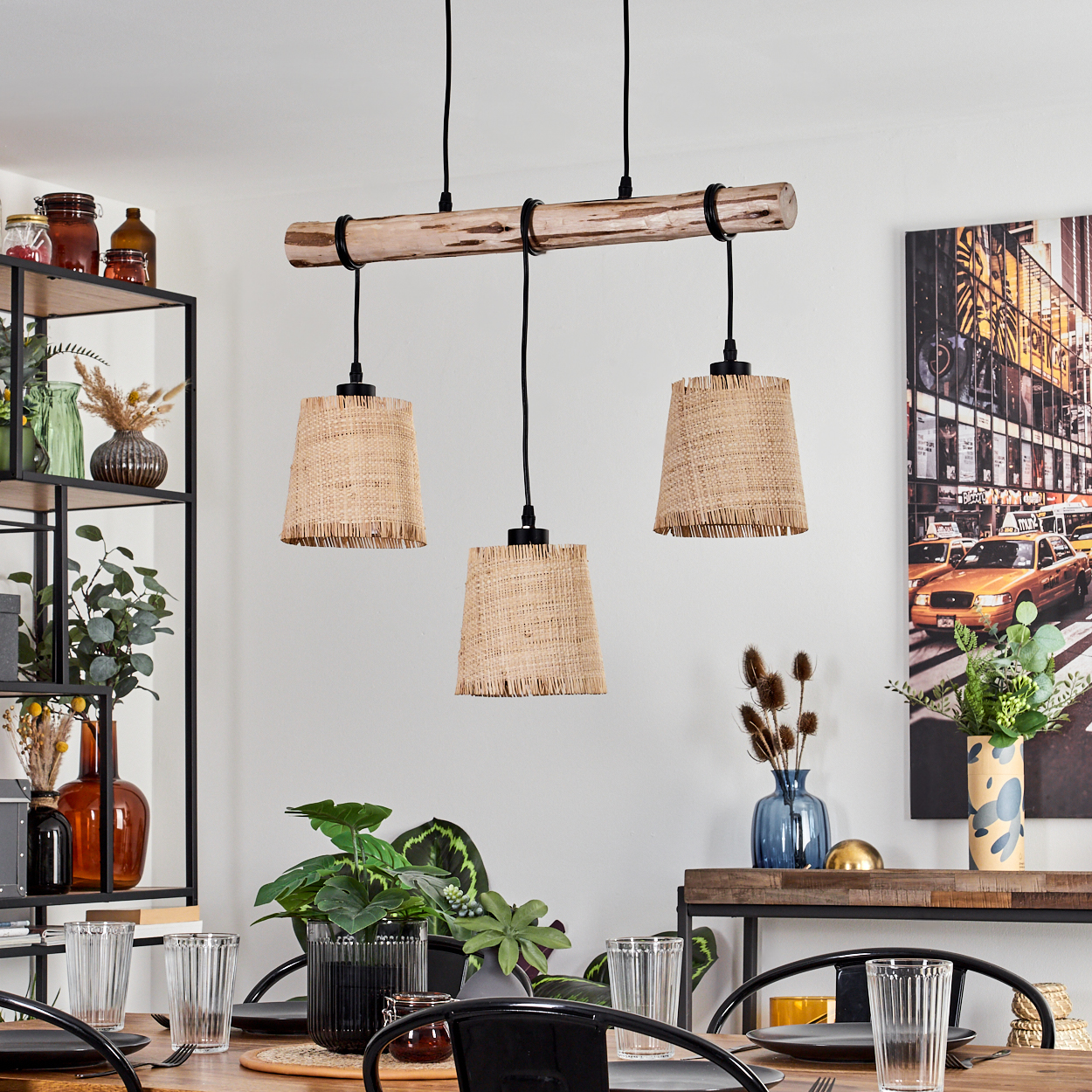 Esszimmer mit Holzbalken-Pendelleuchte, drei Lampen mit Strohschirmen. Ein Tisch ist gedeckt. Kunstwerk von New Yorker Taxis an der Wand.