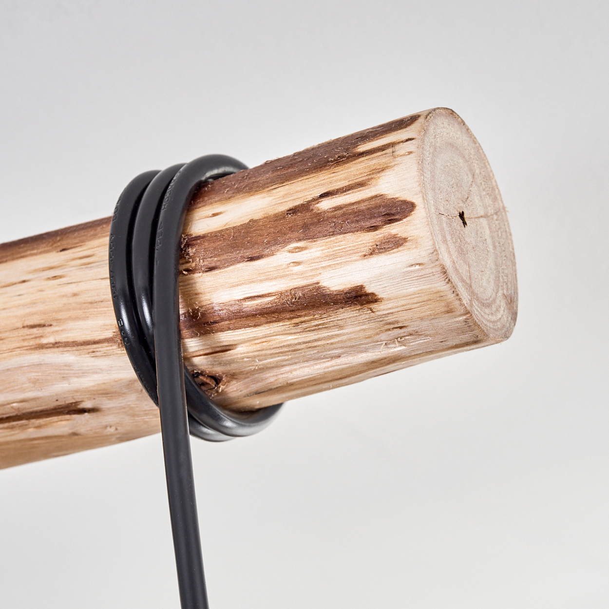 Ein Holzstamm mit einem schwarzen Kabel, das darum gewickelt ist. Der Stamm hat eine hellbraune Farbe, das Kabel ist schwarz. Der Hintergrund ist weiß.