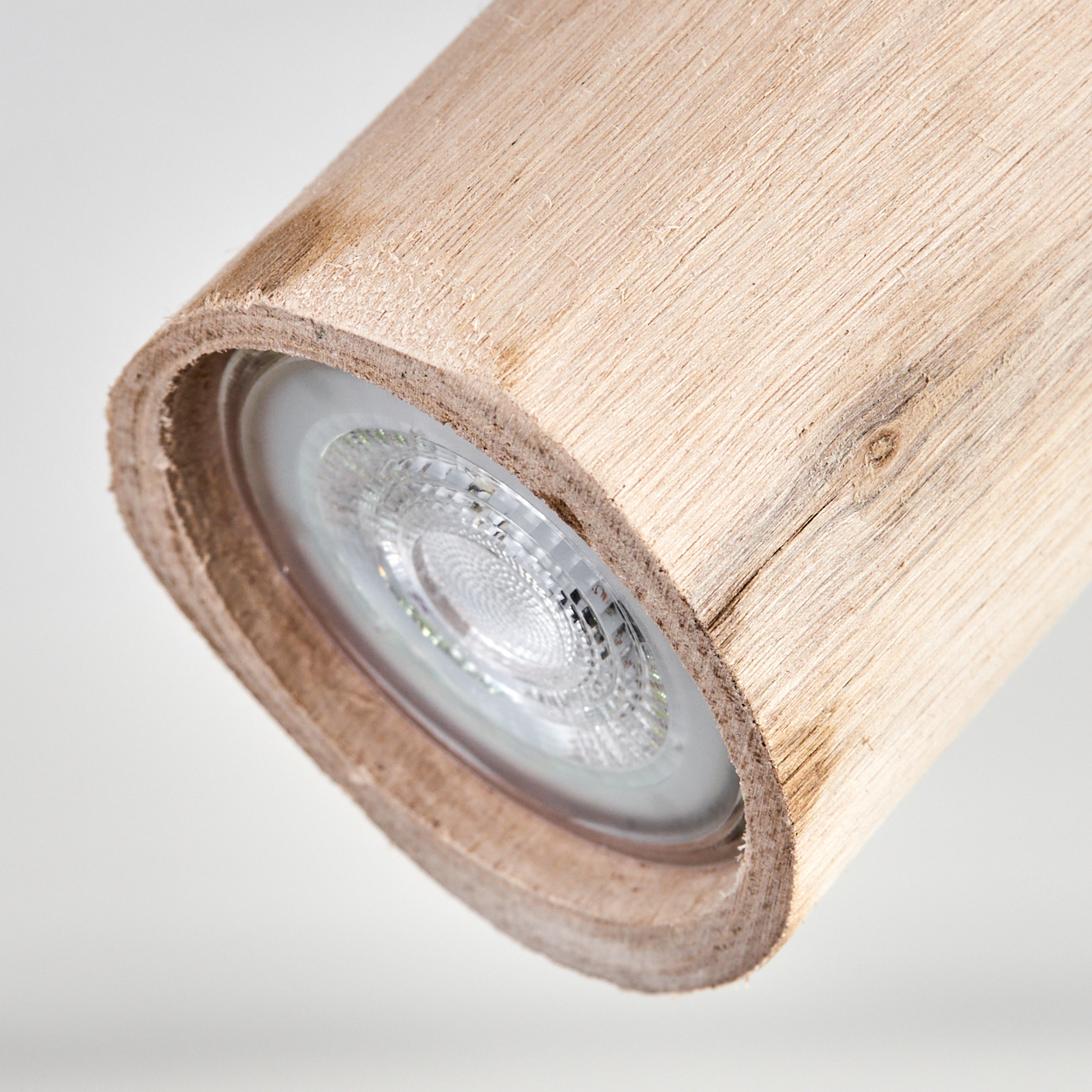 Nahaufnahme einer Holzlampen mit hellem Licht. Das Holz ist hellbraun mit sichtbarer Maserung. Das Licht ist hell und zentriert.