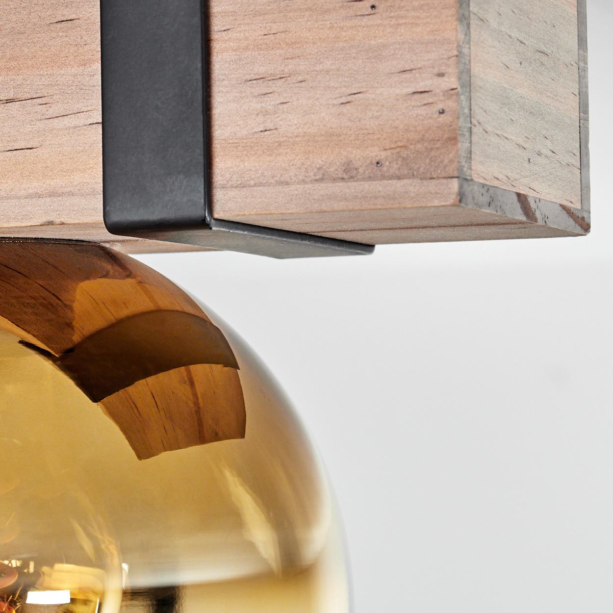 Nahaufnahme einer Lampe. Holzbalken mit Metallstütze über einem Glasschirm. Der Hintergrund ist weiß.