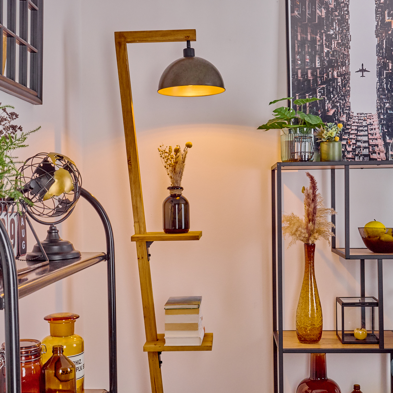 Eine Zimmerecke mit einer Holzlampe, Regalen mit Vasen, Büchern, Pflanzen und einem Stadtbild an der Wand.
