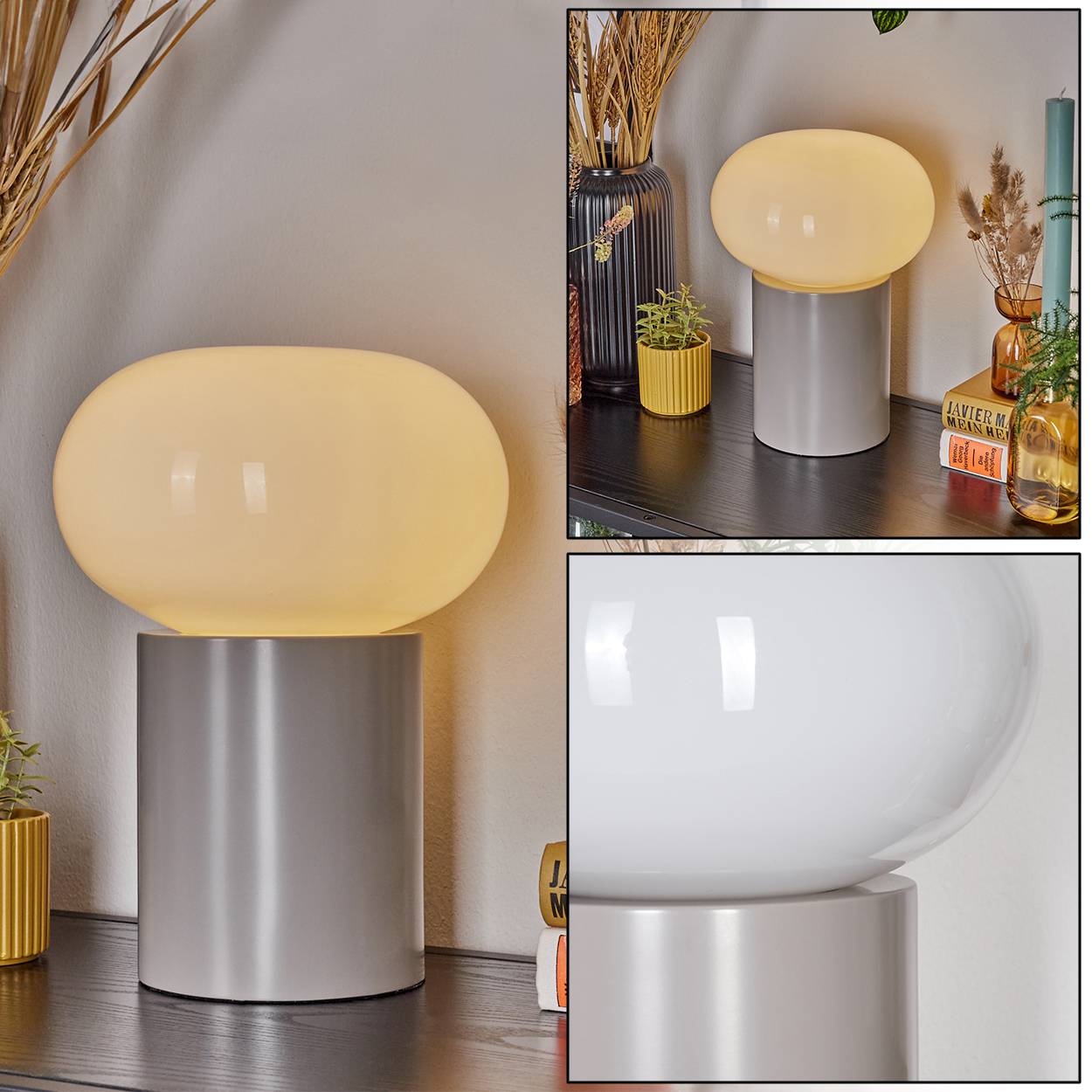 Eine moderne Lampe mit weißem, ovalem Schirm steht auf einem grauen zylindrischen Sockel. Sie steht auf einem dunklen Regal mit Dekoration.