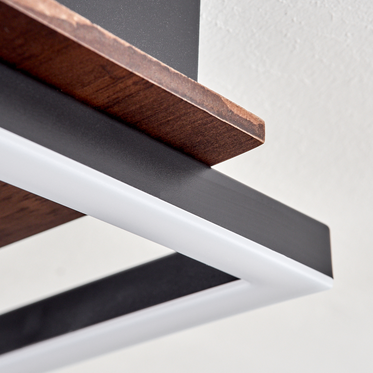 Nahaufnahme eines Holzregals mit schwarzem Rahmen und einer weißen Lichtleuchte. Der Hintergrund ist eine schlichte weiße Wand.