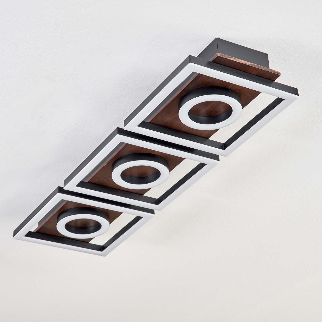 Eine moderne Deckenleuchte mit drei quadratischen Rahmen. Jeder Rahmen hat eine Holzmitte mit einem weißen Ringlicht.