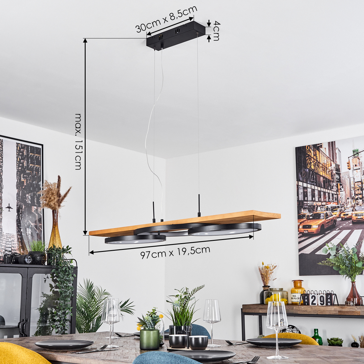 Ein modernes Esszimmer mit Holztisch. Eine stilvolle Deckenlampe hängt darüber. An der Wand befinden sich Dekorationen und ein Gemälde.