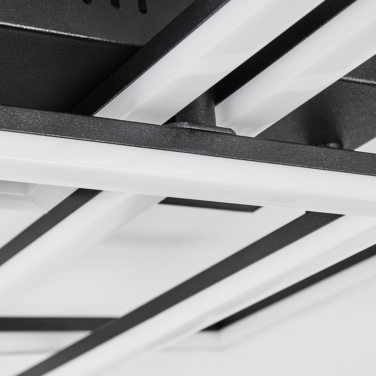 Nahaufnahme einer modernen Deckenleuchte. Sie besteht aus schwarzen Metallrahmen mit integrierten weißen LED-Lichtleisten.