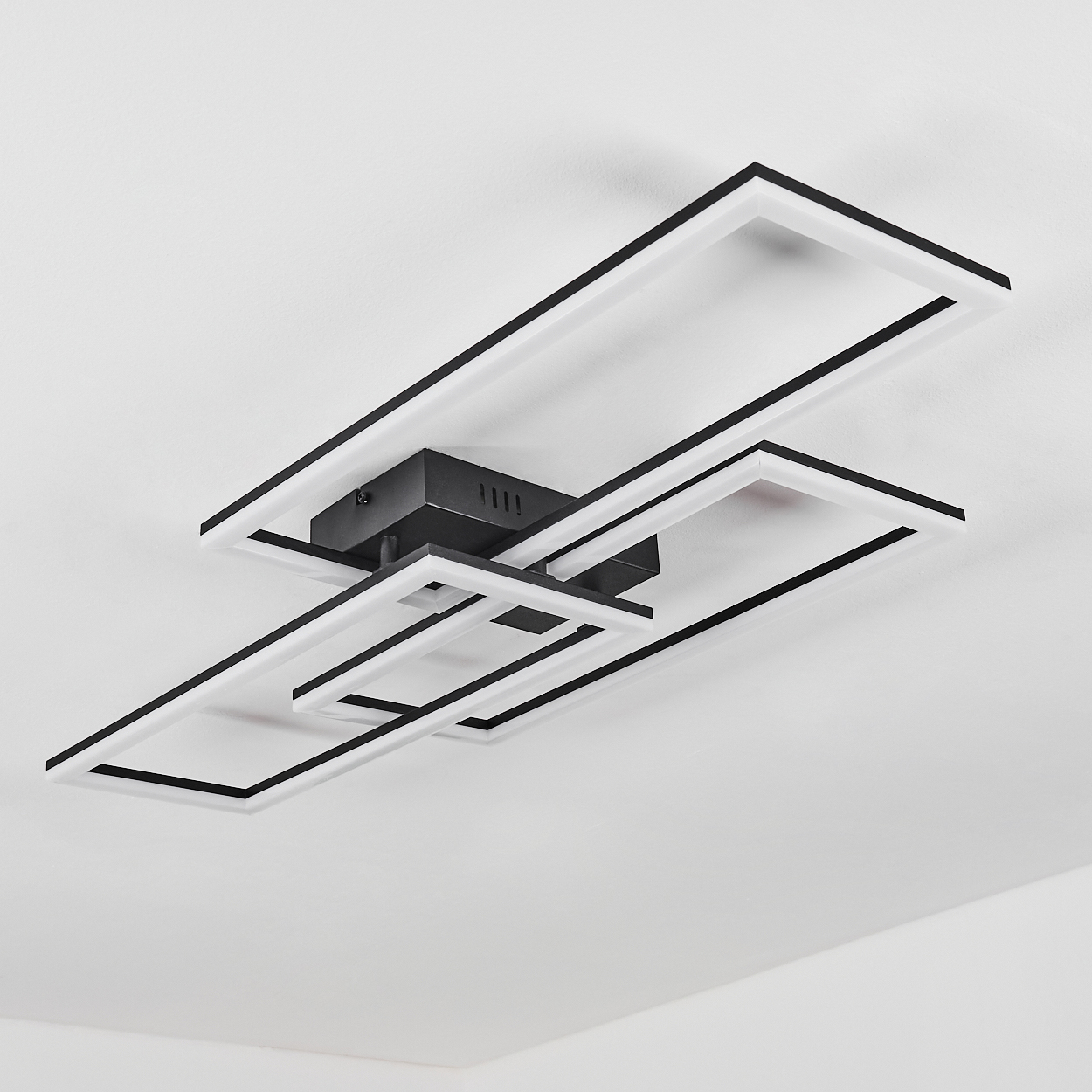 Eine moderne Deckenleuchte mit schwarzen und weißen rechteckigen Rahmen. Sie ist an einer weißen Decke montiert. Die Leuchte hat ein geometrisches Design.