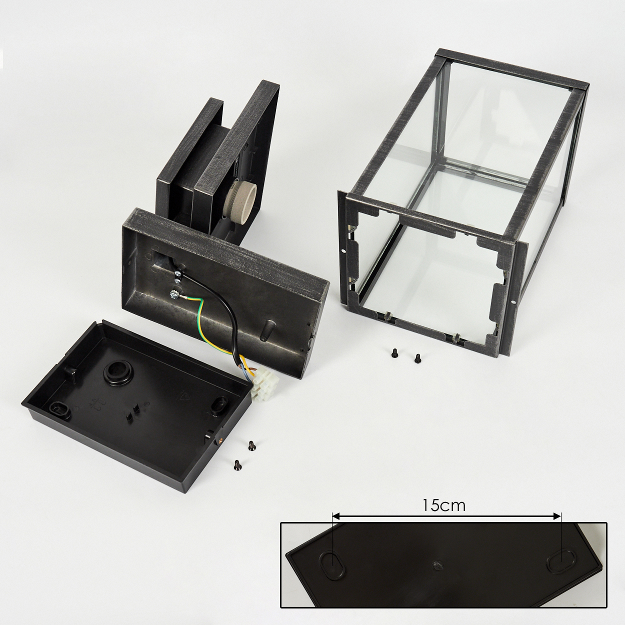 Zerlegte Teile einer Außenlampe auf Weiß. Enthält einen Glasrahmen, Metallsockel, schwarze Abdeckung und 15 cm Messung. Schrauben sichtbar.