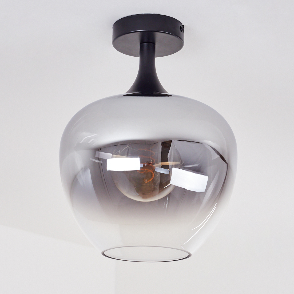 Moderne Deckenleuchte. Sie hat einen schwarzen Sockel und Stiel sowie einen grauen, kugelförmigen Glasschirm mit sichtbarer Glühbirne.