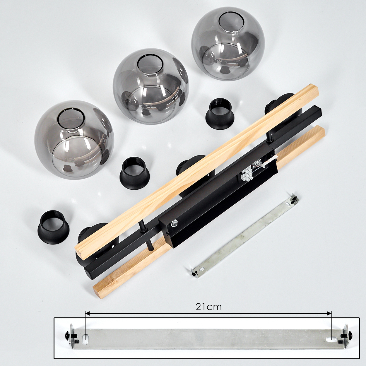 Komponenten einer Leuchte, darunter Glaskugeln, schwarze Ringe, Holz- und Metallstäbe sowie eine 21 cm lange Metallhalterung.