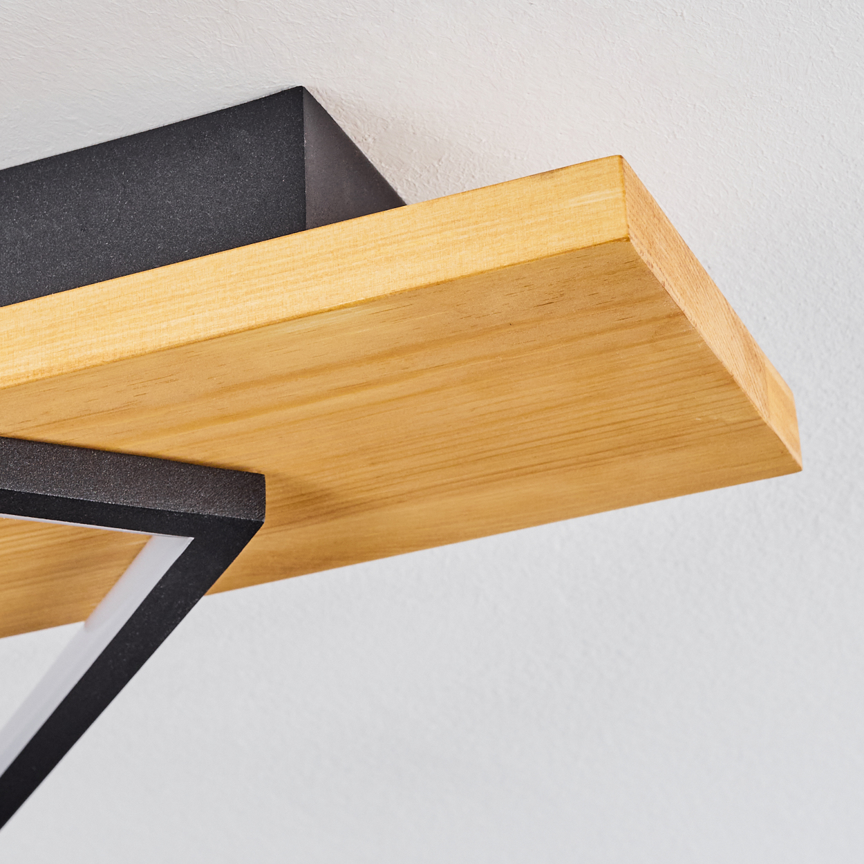 Holzregal mit schwarzen Metallstützen an einer weißen Wand. Nahaufnahme zeigt Holzmaserung.