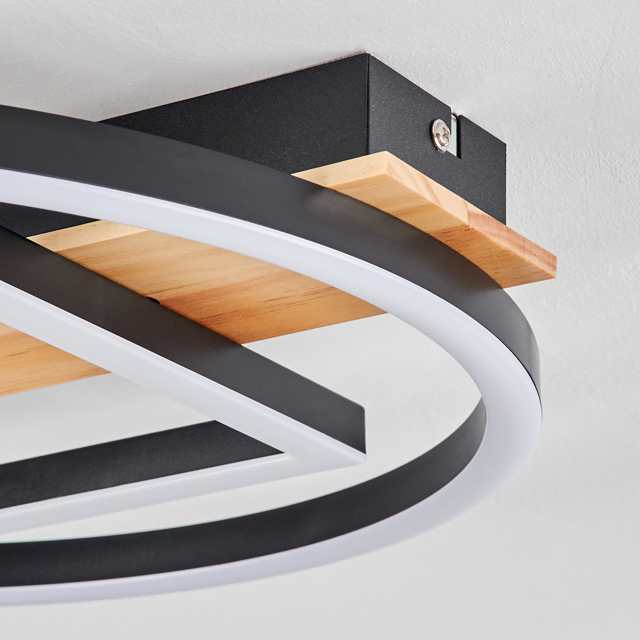 Eine moderne Deckenleuchte mit kreisförmigem Design. Sie hat schwarze Metallrahmen mit weißen LED-Streifen und Holzakzenten, montiert an einer weißen Decke.