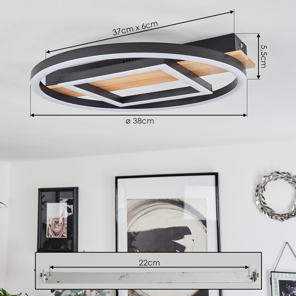 Eine moderne Deckenleuchte mit Maßen. Die Lampe ist schwarz, Holz und weiß. Unten sind gerahmte Bilder und ein Kranz zu sehen.
