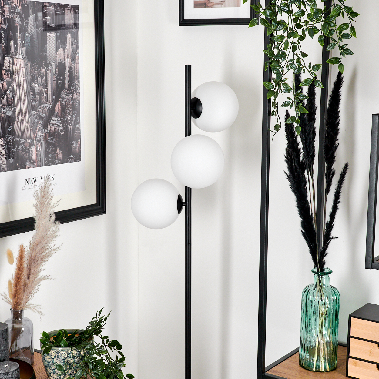 Ein modernes Interieur mit einer schwarzen Stehlampe mit drei weißen Kugellampen. Ein New York City-Druck ist an der Wand.
