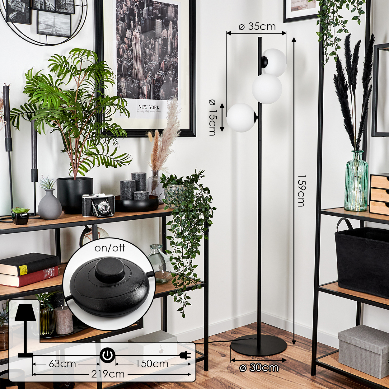Wohnzimmer mit Regalen, Pflanzen, einer Stehlampe mit drei weißen Kugeln, einem New York-Druck und einem runden Ein/Aus-Schalter.