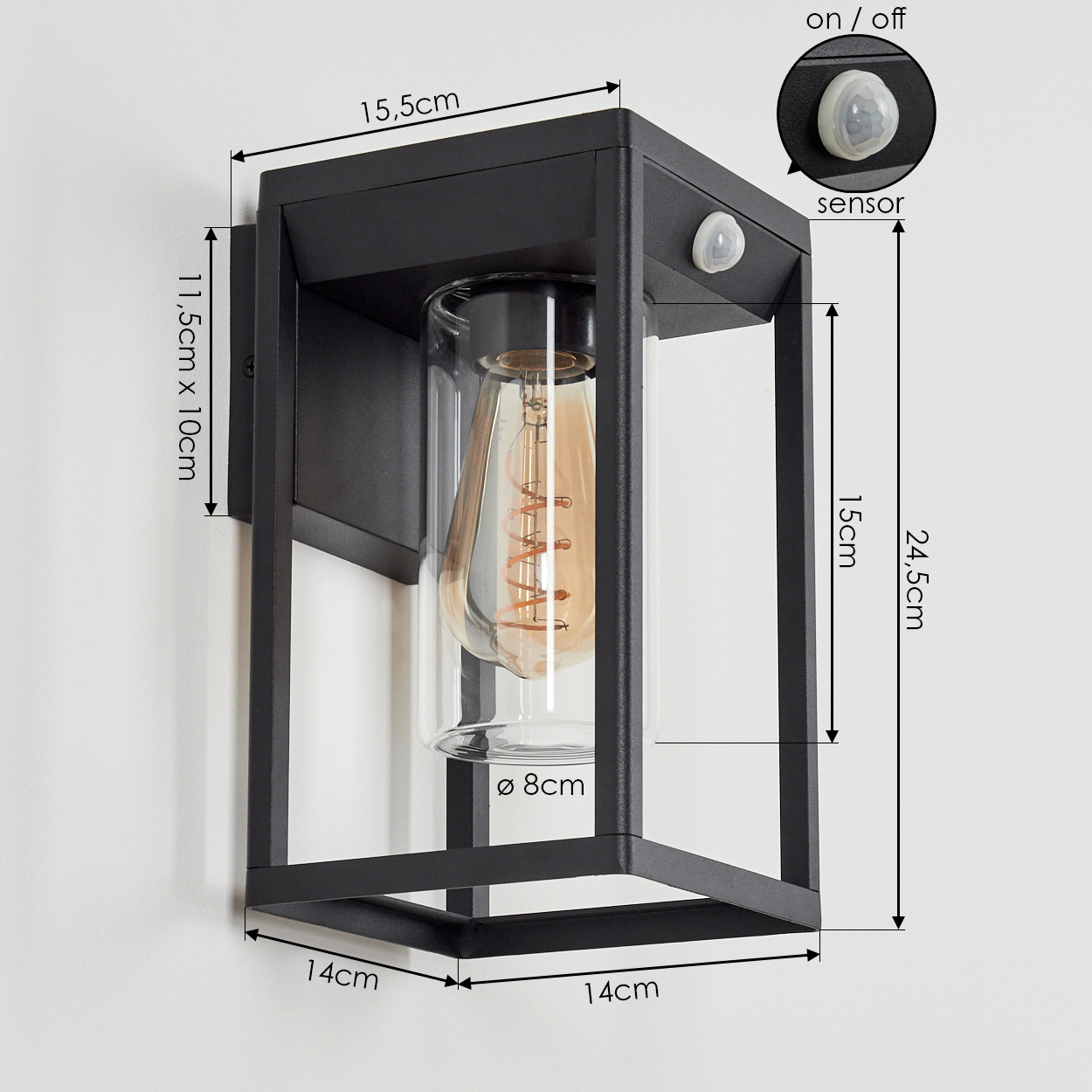 Schwarze Außenwandleuchte mit Abmessungen. Verfügt über einen Sensor und eine Edison-Glühbirne in einem Glaszylinder. An einer weißen Wand montiert.
