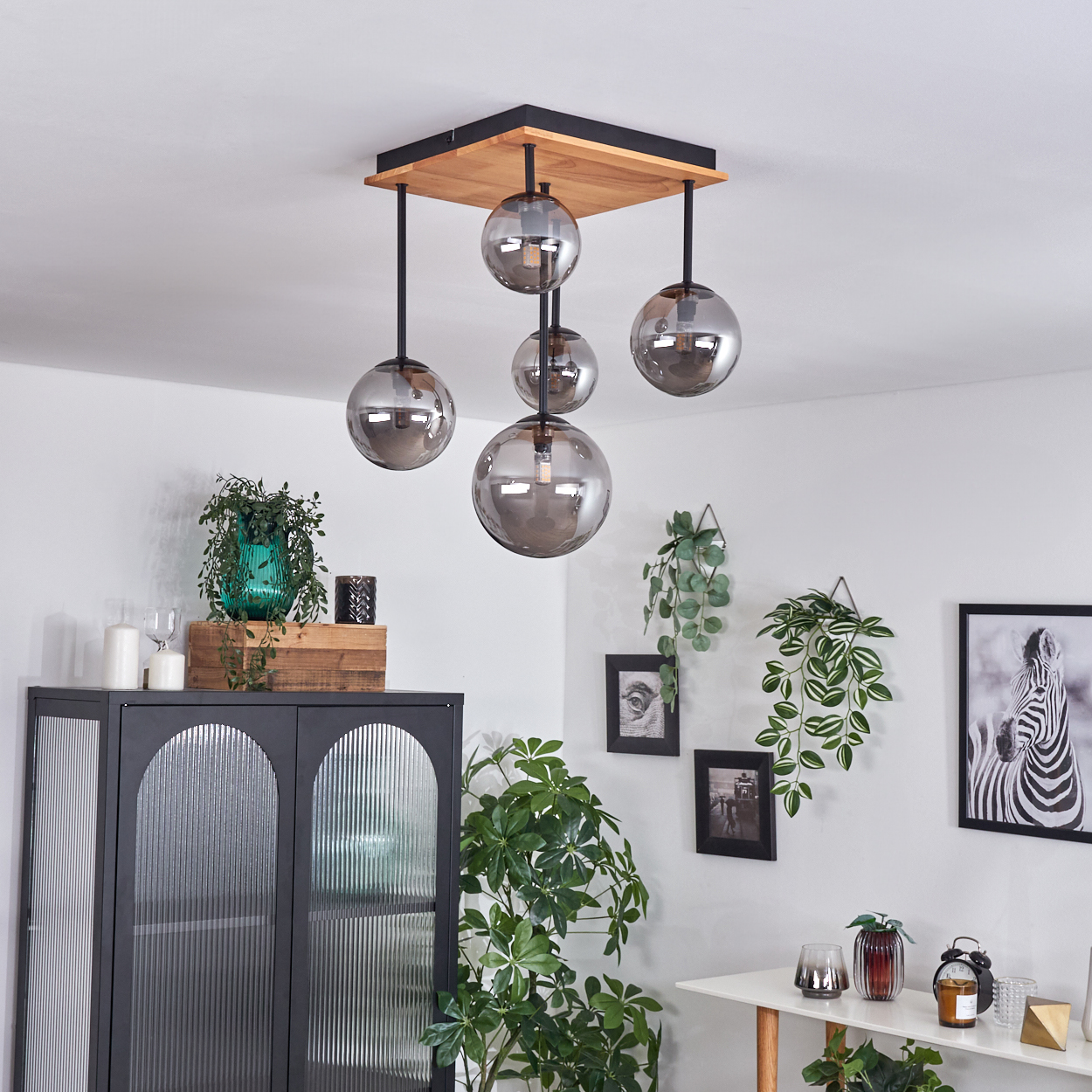 Modernes Wohnzimmer mit Deckenlampe und Deko. Pflanzen, Schrank, Bilder und Zebra-Druck.