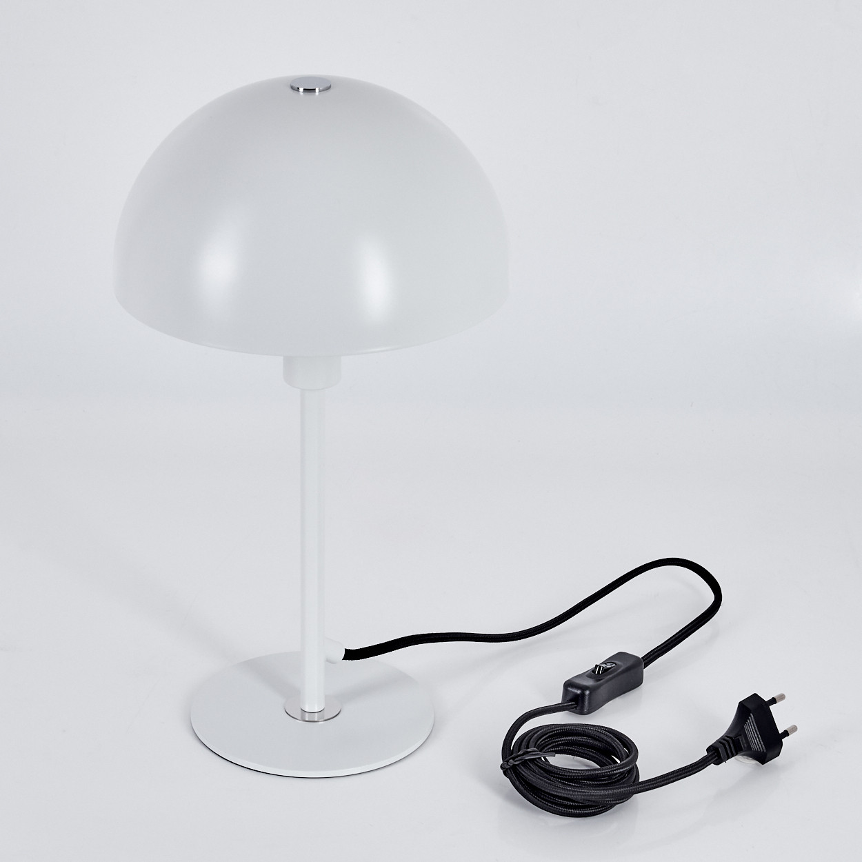 Eine weiße Schreibtischlampe mit kuppelförmigem Schirm, zylindrischem Stiel und kreisförmigem Fuß. Ein schwarzes Netzkabel ist angeschlossen.
