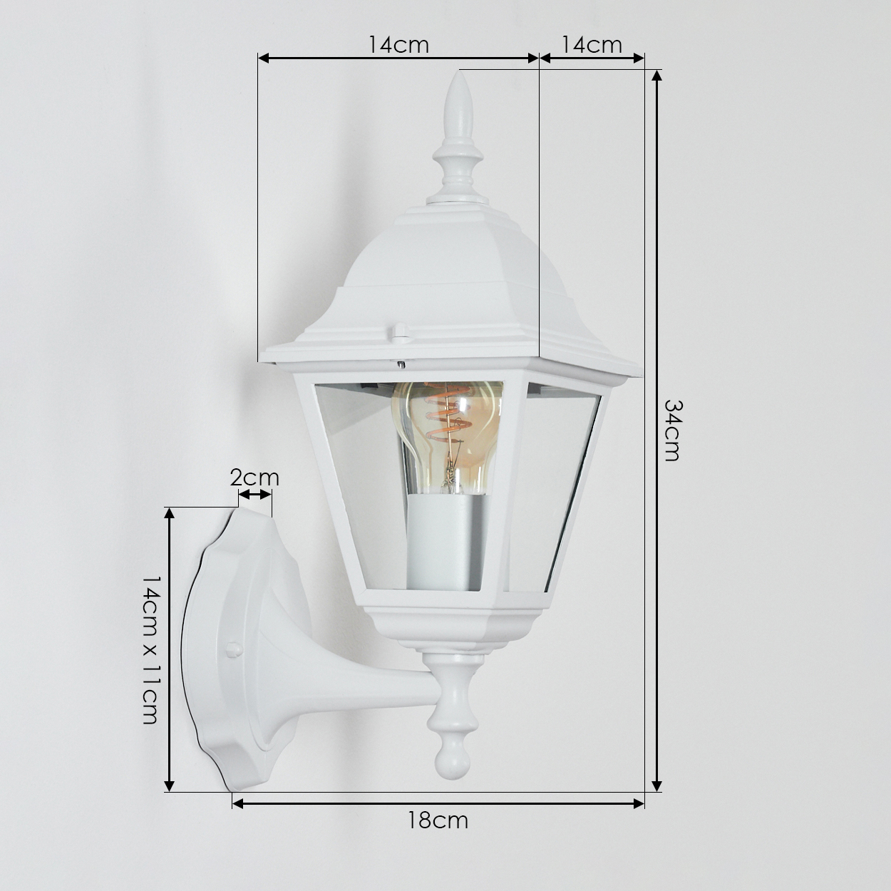 Weiße Wandlampe mit Maßangaben. Sie hat eine Glühbirne im Inneren, mit Glasscheiben und dekorativen Elementen. An einer weißen Wand montiert.