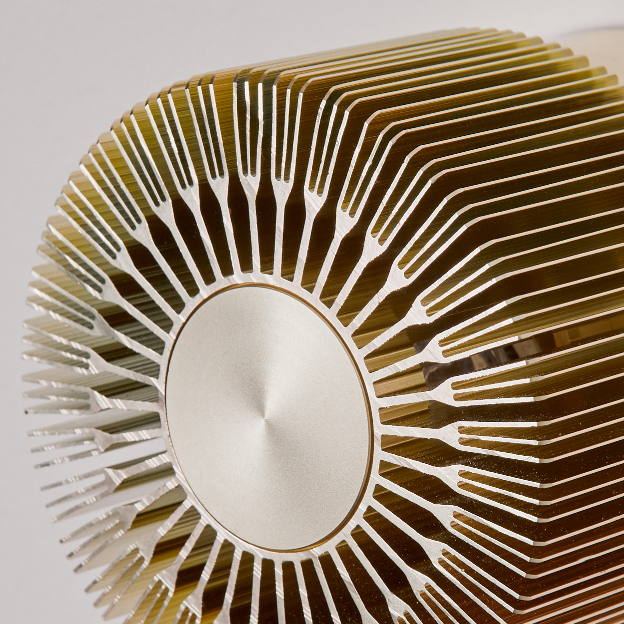 Nahaufnahme eines metallischen CPU-Kühlers mit radialen Lamellen. Der Kühler hat eine silberne zentrale Scheibe und goldfarbene Lamellen. Der Hintergrund ist weiß.