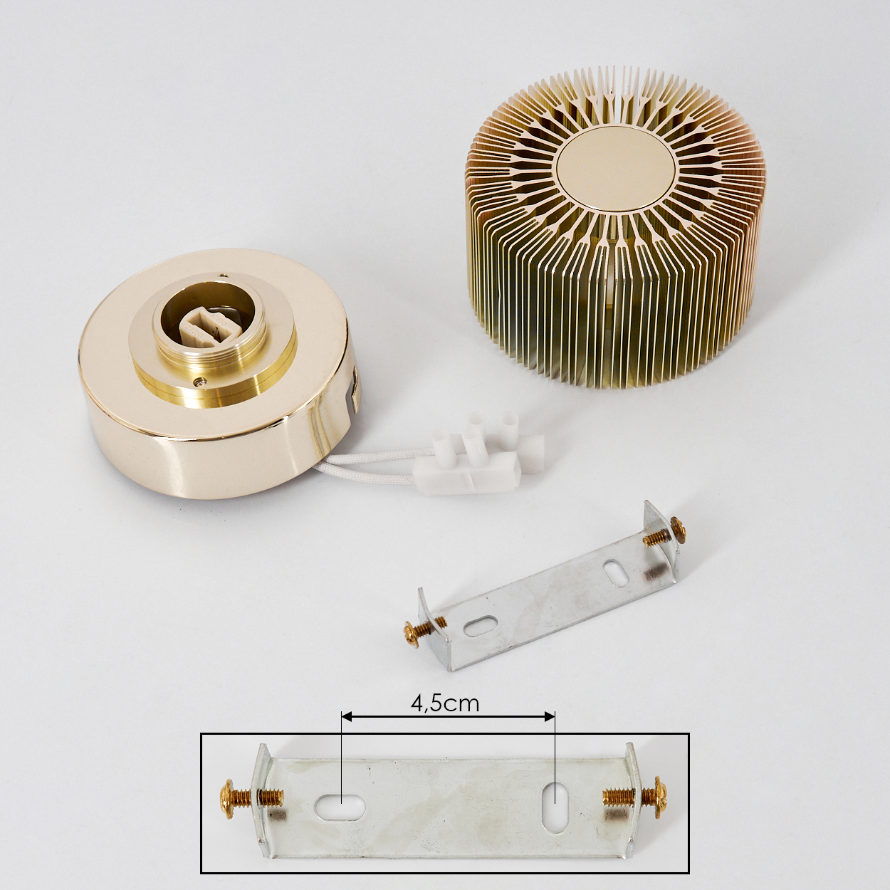 Komponenten einer Lampe auf weißer Oberfläche. Teile: runder Sockel, zylindrischer Kühlkörper und Metallhalterung.