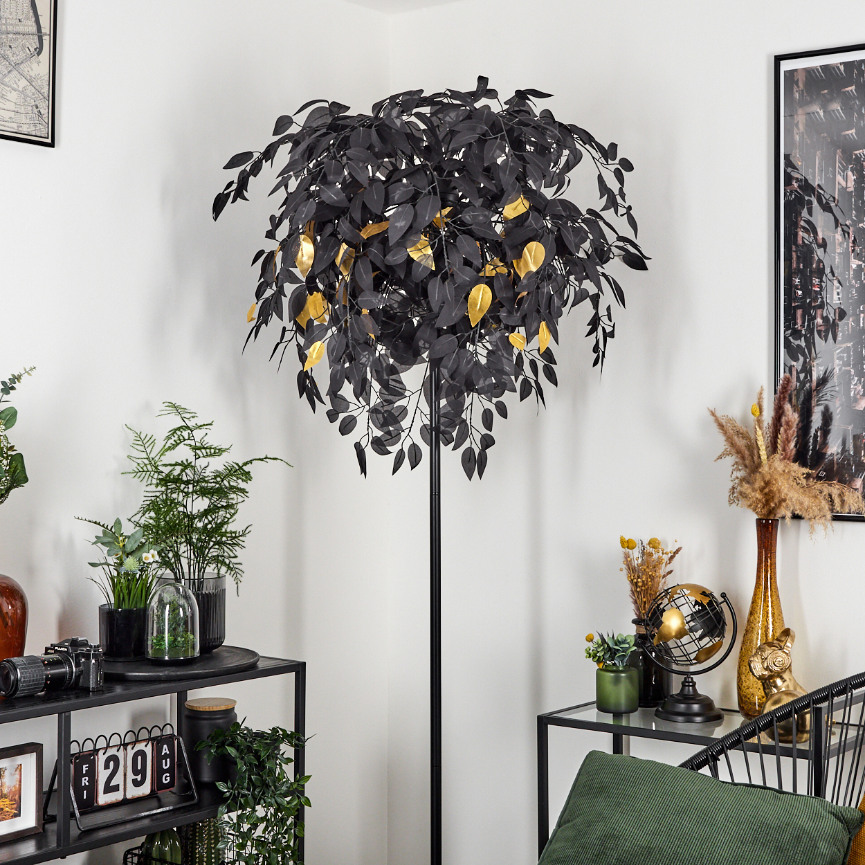 Eine Zimmerecke mit einem Baum mit schwarzen und goldenen Blättern, Pflanzen, Regalen mit Dekorationen und einem Stuhl mit grünem Kissen.