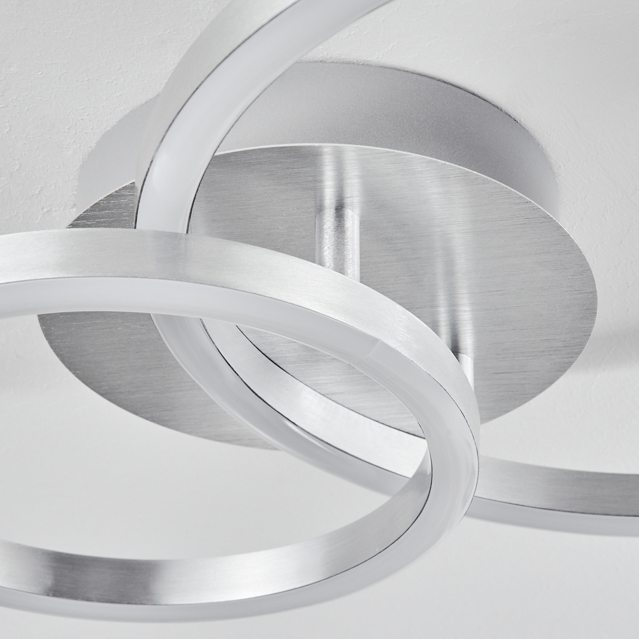 Nahaufnahme einer modernen Deckenleuchte. Sie hat drei ineinandergreifende silberne Ringe mit weißen LED-Leuchten, die an einer kreisförmigen Basis befestigt sind.
