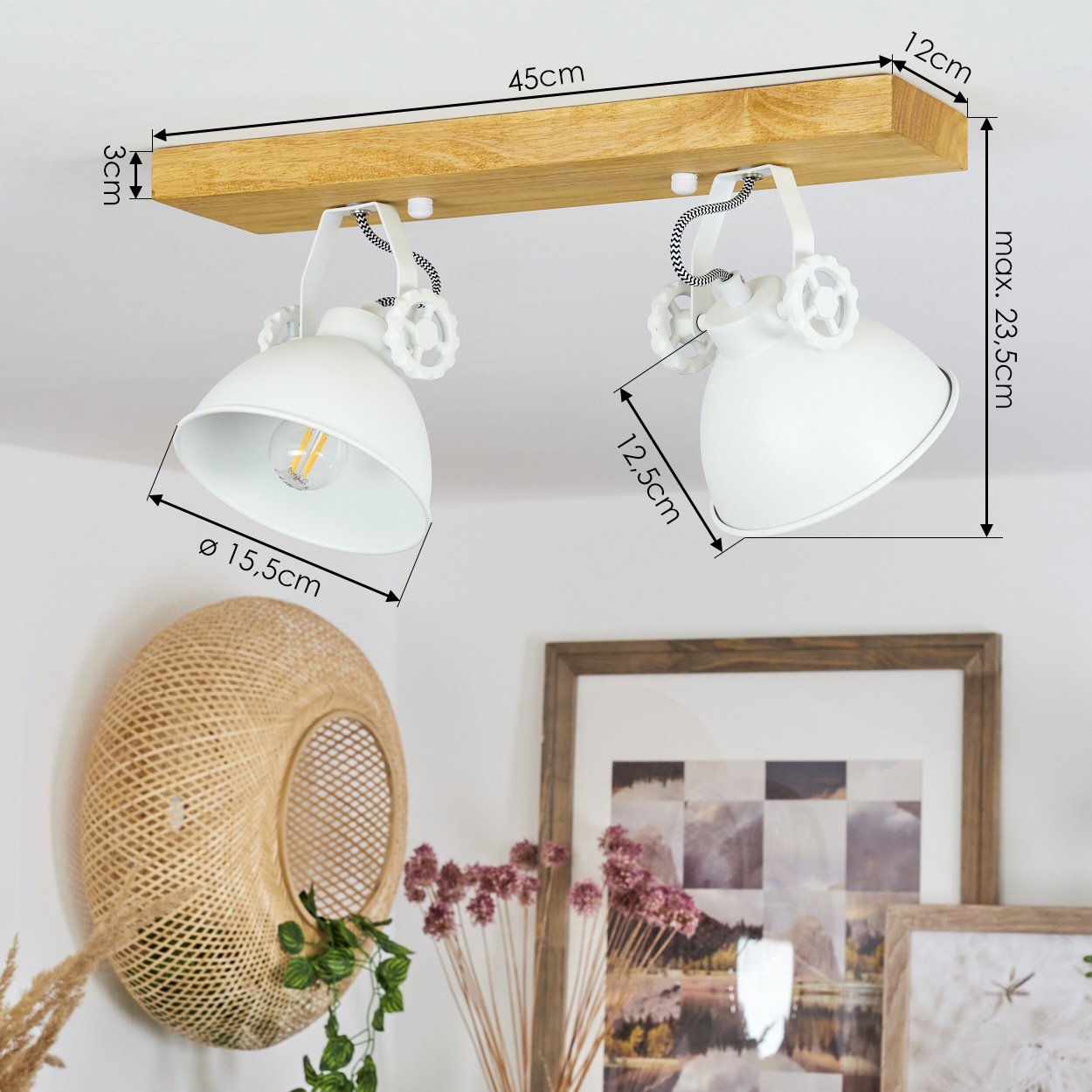 Weiße Deckenlampe mit zwei Lichtern auf Holzbrett. Wanddekoration aus Korb, gerahmte Bilder und Trockenblumen im Hintergrund.