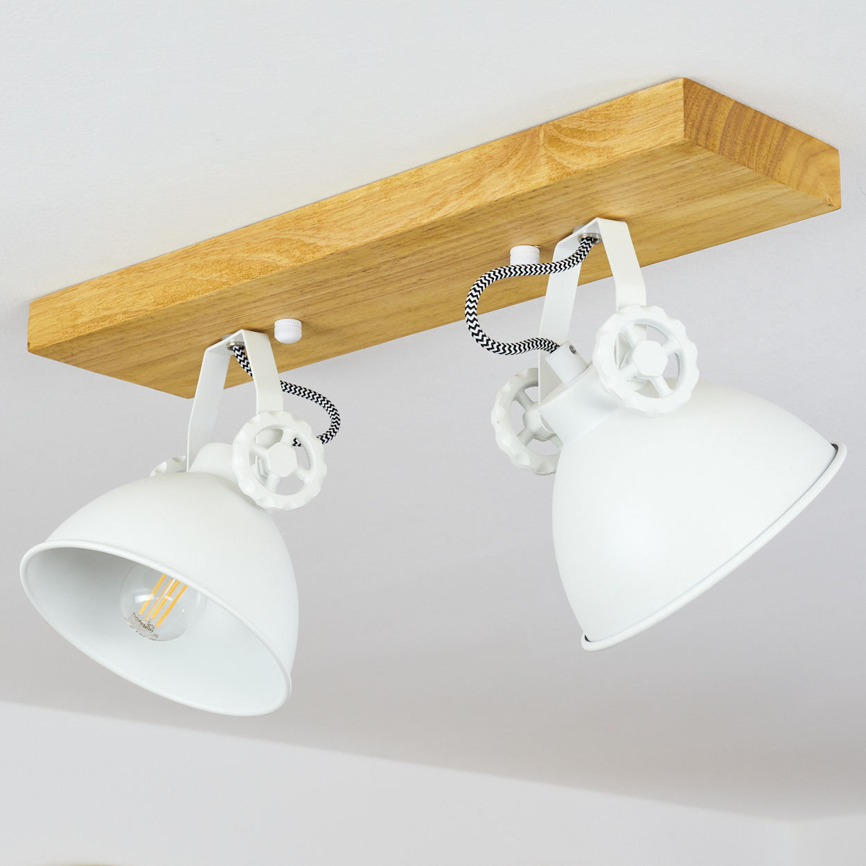 Eine Deckenleuchte mit zwei weißen Lampen, die an einem Holzbalken befestigt sind. Die Lampen haben ein Retro-Design und sind vor einer weißen Decke.