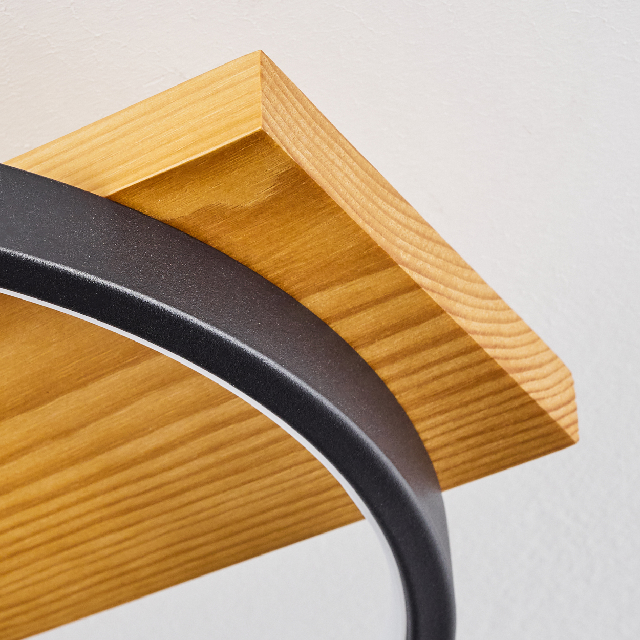 Ein Holzregal mit schwarzer Metallstütze vor einer weißen Wand. Das Regal hat eine natürliche Holzmaserung.