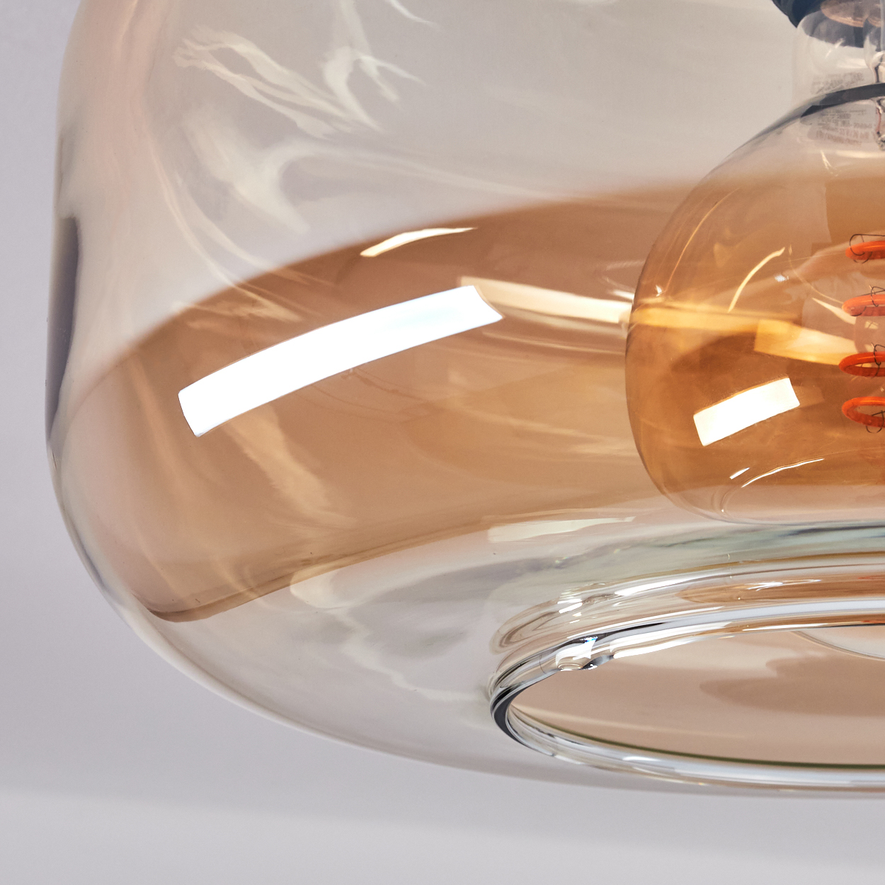 Nahaufnahme eines Glasobjekts, möglicherweise eine Lampe oder ein Dekorationsstück. Es besteht aus klarem und bernsteinfarbenem Glas mit reflektierender Oberfläche.