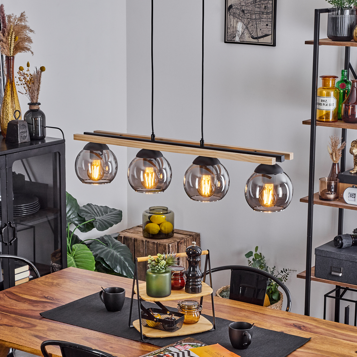 Ein Esszimmer mit Holztisch, vier Pendelleuchten und einem Regal mit Dekoelementen. Die Leuchten haben kugelförmige Glasschirme.