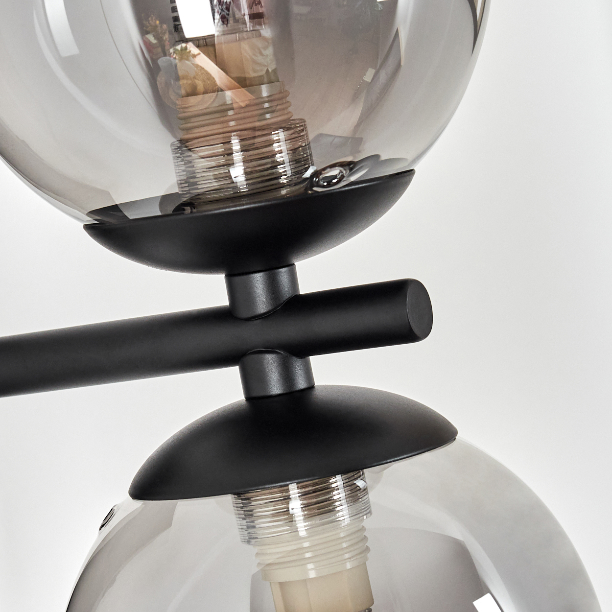 Nahaufnahme einer schwarzen Metalllampe mit zwei Glaskugeln. Jede Kugel hat eine Glühbirne. Der Hintergrund ist weiß.