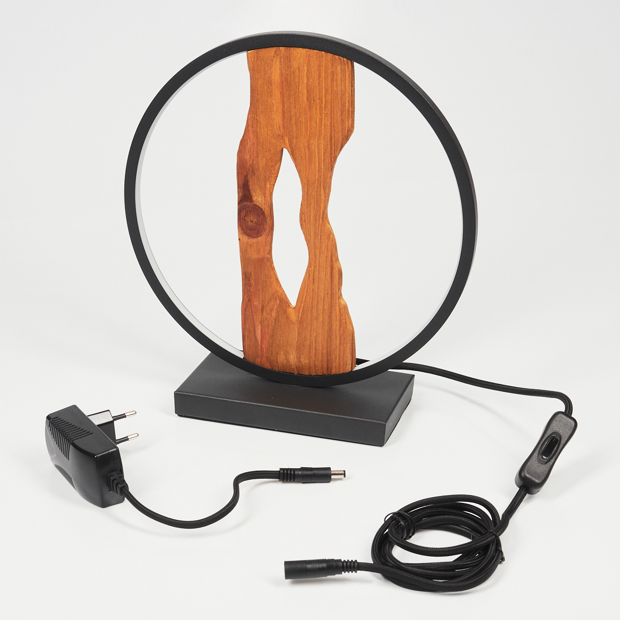 Eine moderne Holzlampe mit schwarzem kreisförmigem Rahmen, Holzkern und schwarzen Kabeln, die mit einem Netzteil und Schalter verbunden sind.