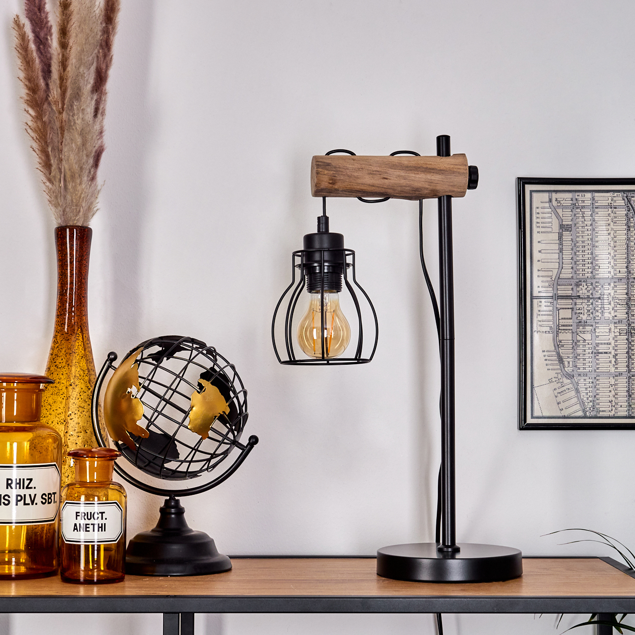 Eine Schreibtischszene mit Lampe, Globus, Vasen und gerahmter Karte. Die Lampe hat eine Holzplatte und eine vergitterte Glühbirne.