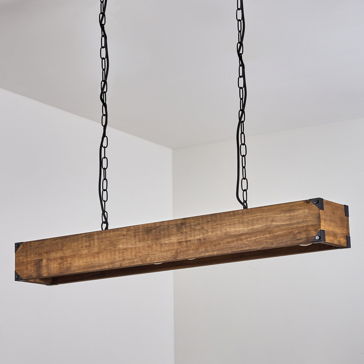 Eine rechteckige Holzlampen hängt an schwarzen Ketten von der Decke. Die Lampe hat eine hellbraune Farbe und ist vor einem weißen Hintergrund platziert.