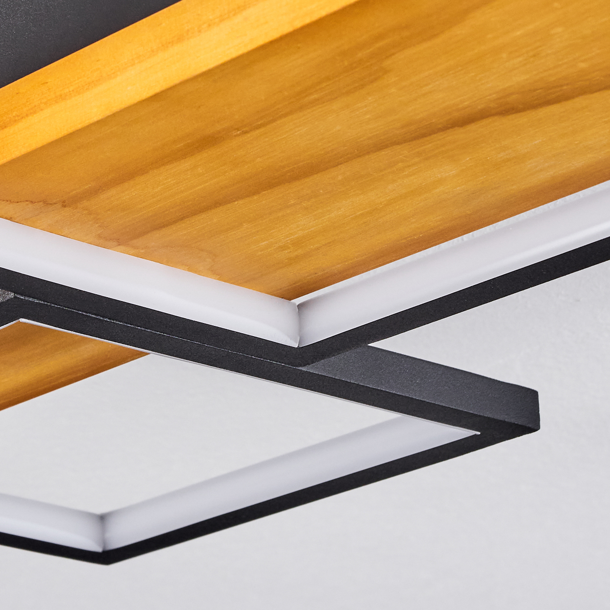 Nahaufnahme einer modernen Deckenleuchte. Sie verfügt über Holzpaneele, einen weißen und schwarzen geometrischen Rahmen.