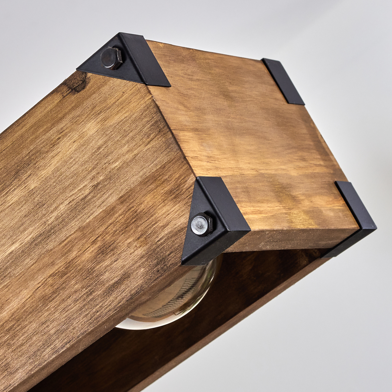 Nahaufnahme einer Holzlampe. Sie hat Metallhalterungen, eine Glühbirne im Inneren und einen weißen Hintergrund.