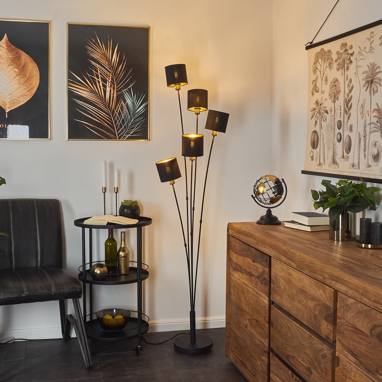 Ein Raum mit Stehlampe, Kunst und Schrank. Eine schwarze Lampe mit fünf Schirmen. Der Raum hat einen Globus.