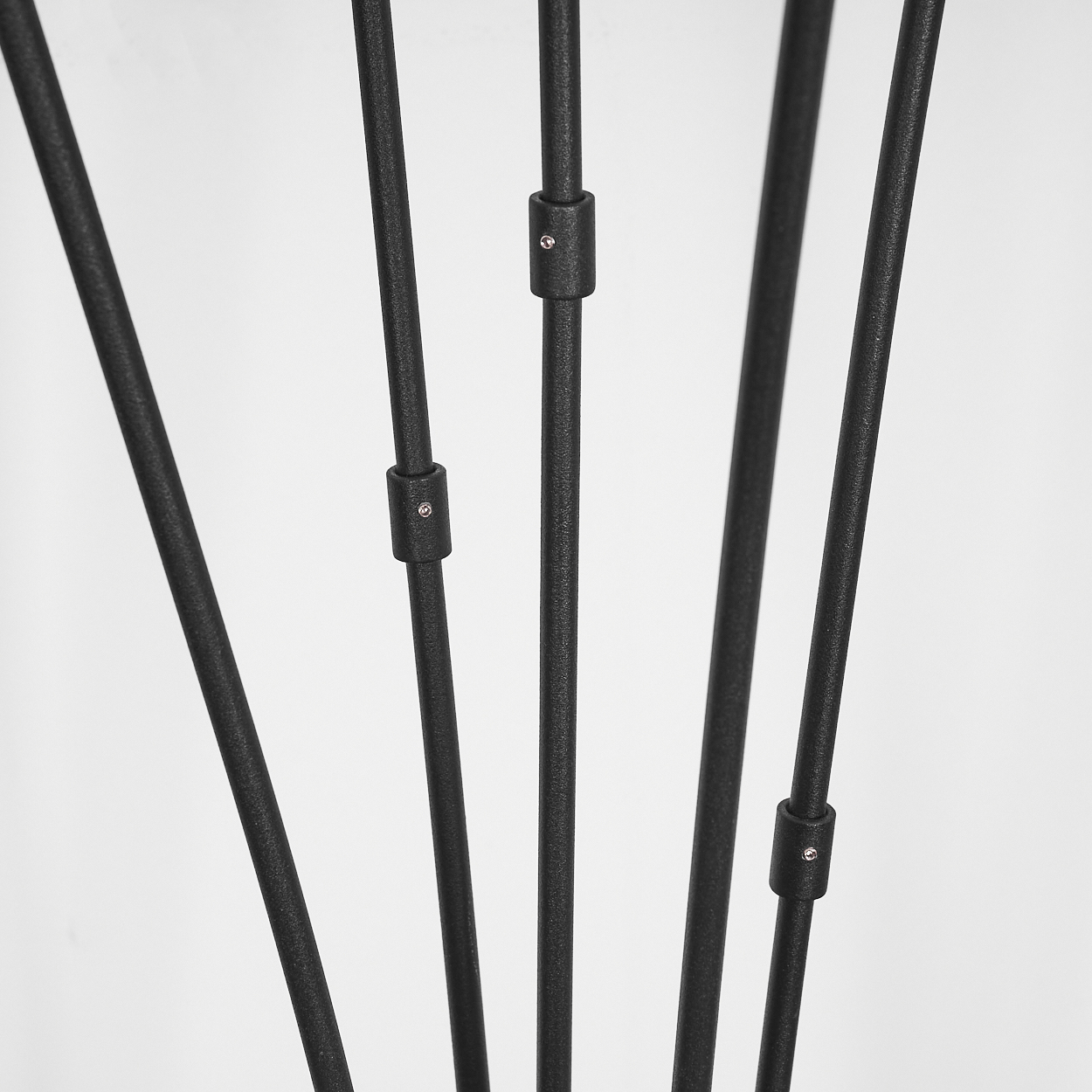 Nahaufnahme von schwarzen Metallstangen, verbunden durch kleine schwarze Verbinder. Der Hintergrund ist weiß.
