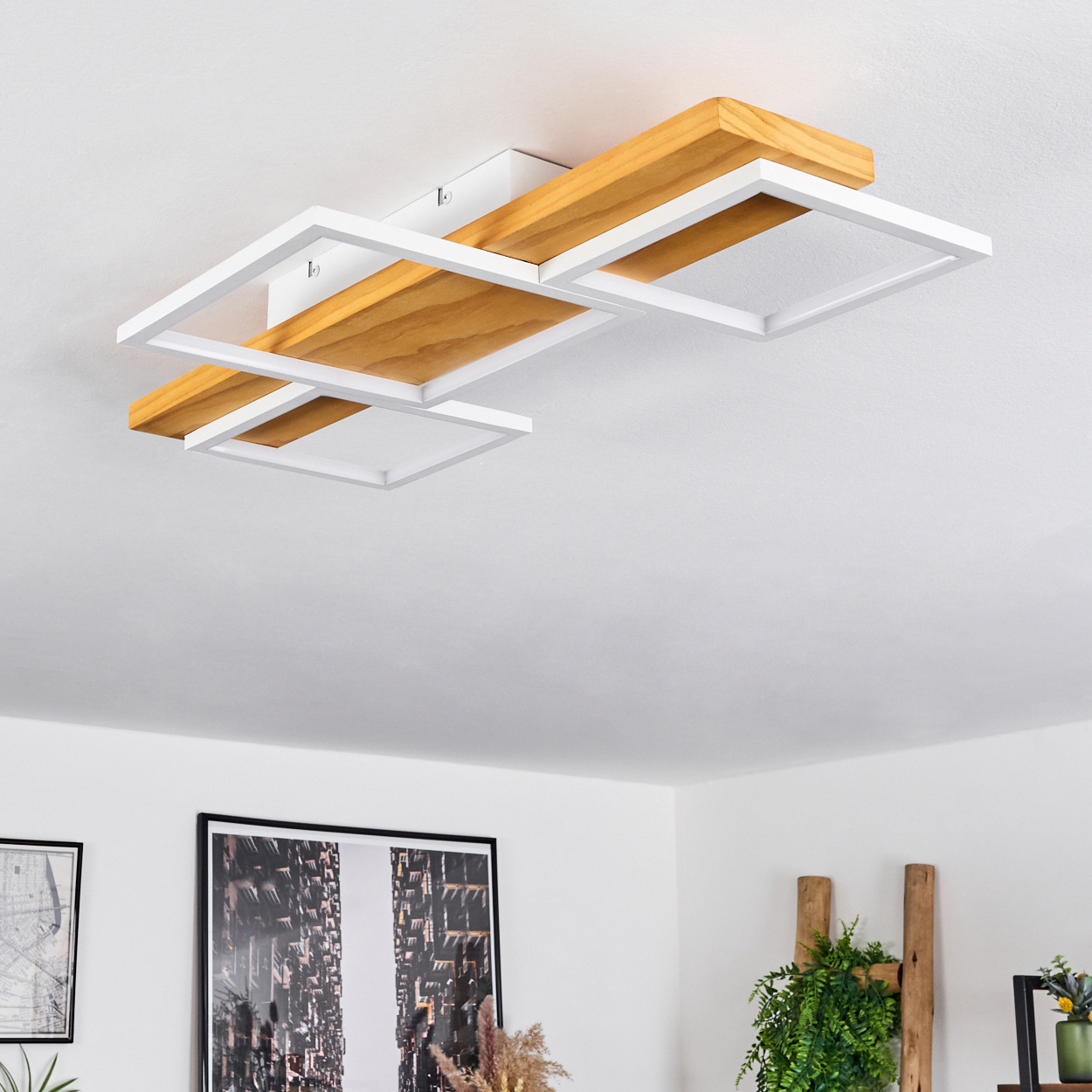 Moderne Deckenleuchte mit Holz- und weißen quadratischen Rahmen. Hintergrund: weiße Decke und Wände, Kunst, Pflanzen, Leiter.