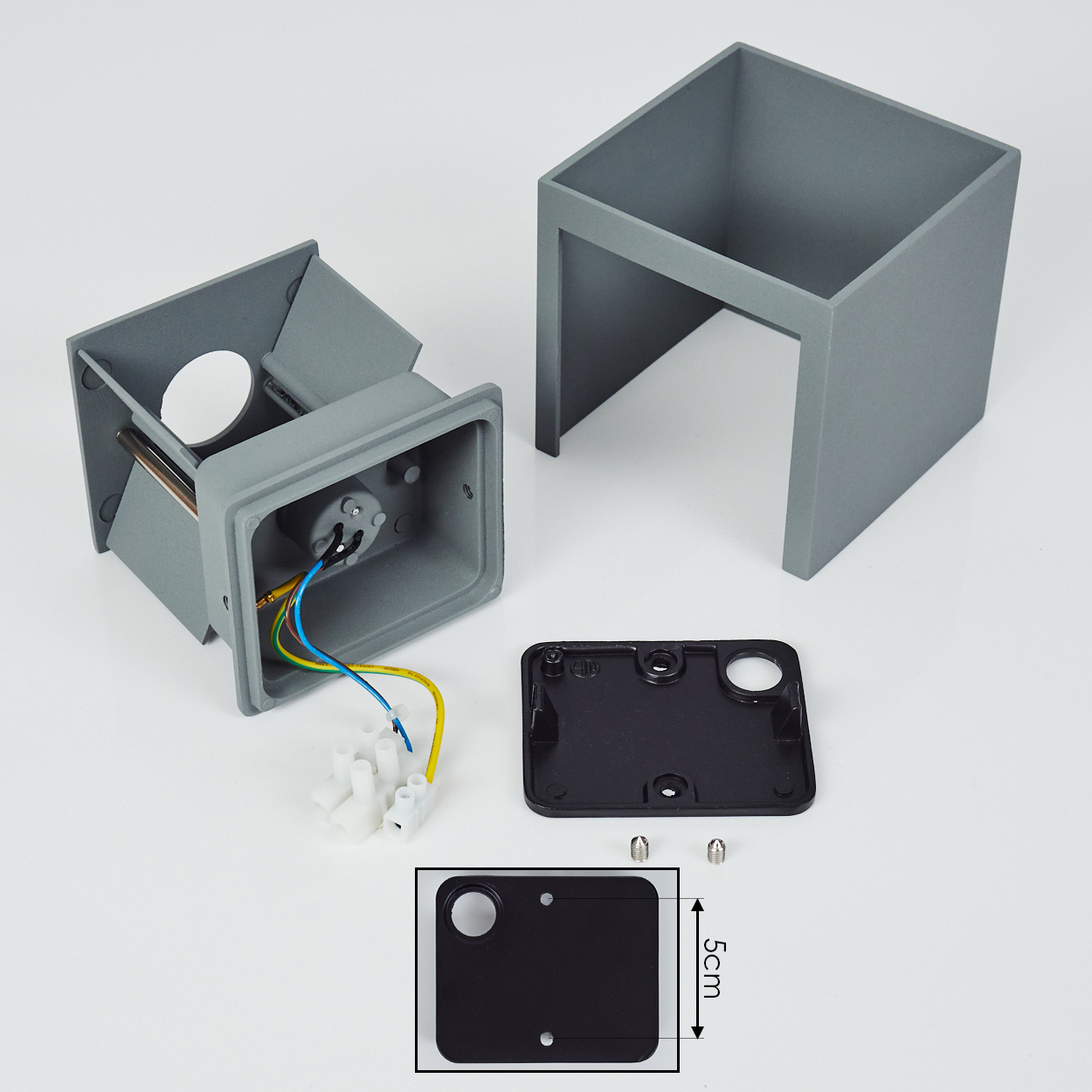Zerlegte graue elektrische Gehäusekomponenten auf weißem Untergrund. Enthält Box, Abdeckung, Drähte und Schrauben. Eine schwarze Abdeckung wird hervorgehoben.