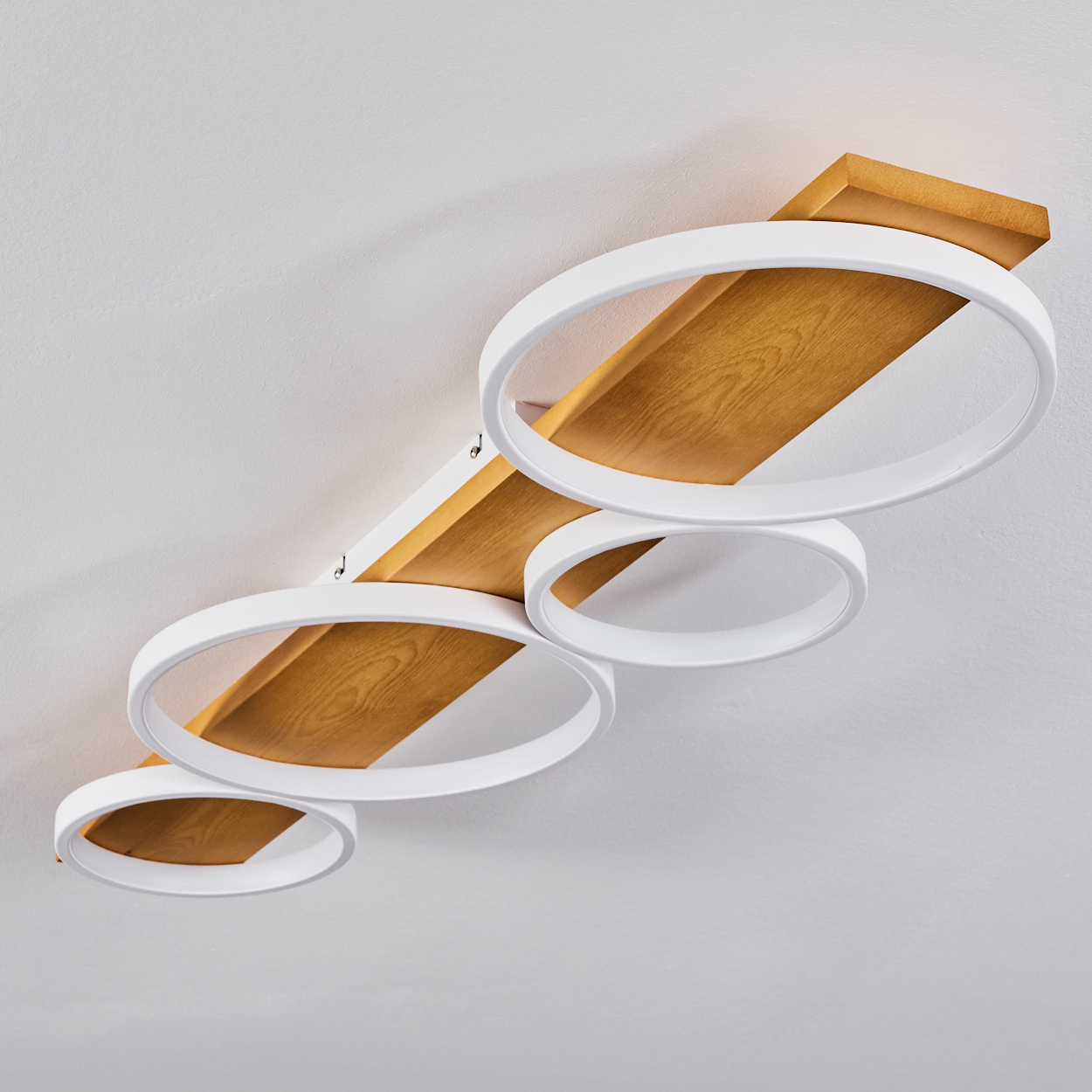 Moderne Deckenleuchte. Sie hat ein Holzbrett mit weißen kreisförmigen Lichtern. Der Hintergrund ist eine weiße Decke.