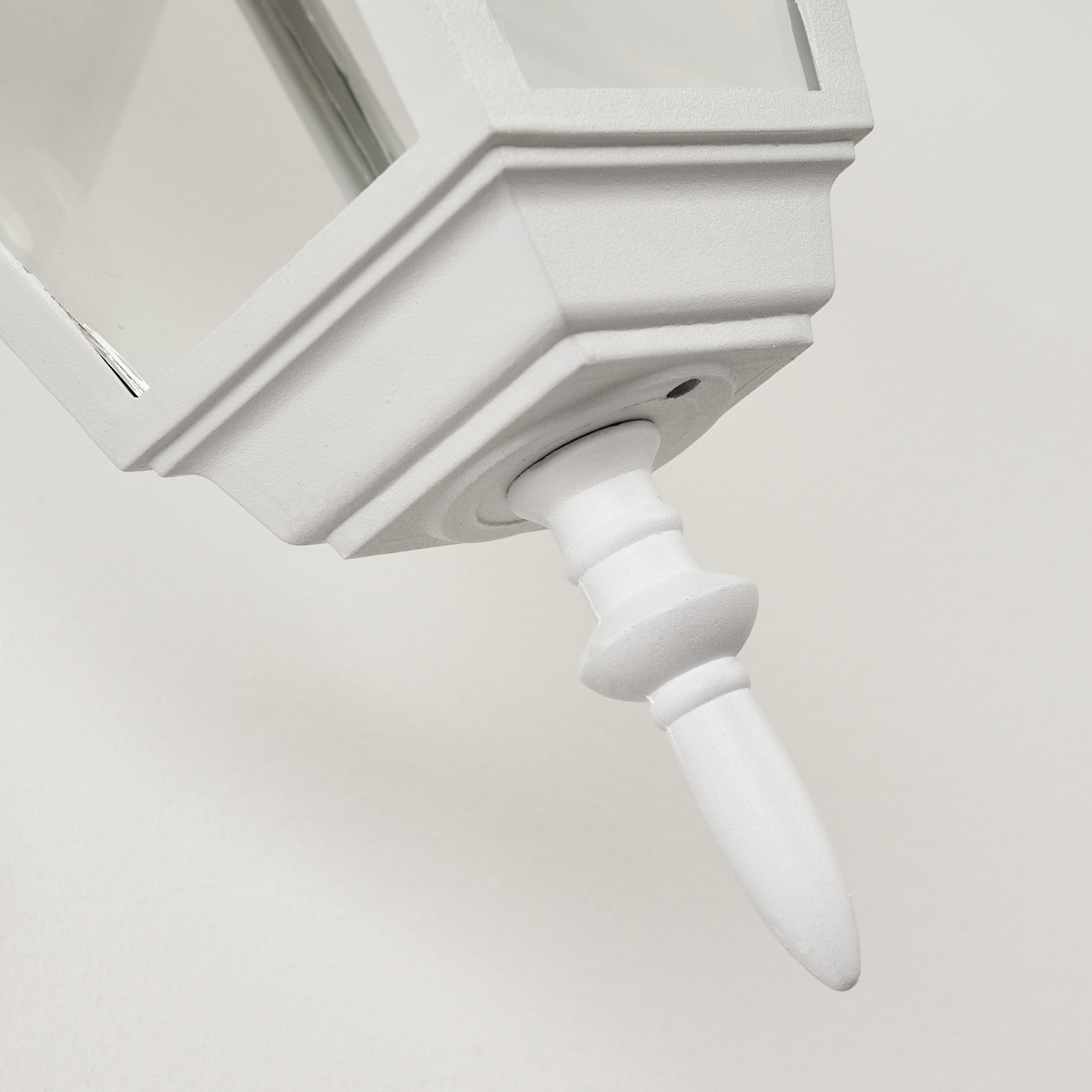 Nahaufnahme einer weißen, verzierten Struktur, möglicherweise eine Leuchte, vor einer schlichten weißen Wand. Die Struktur hat ein dekoratives Design.