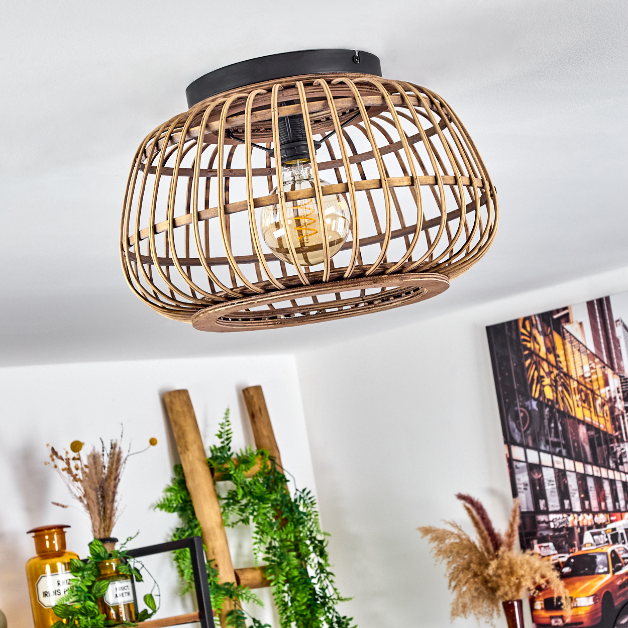 Eine hölzerne, käfigartige Deckenlampe mit sichtbarer Glühbirne hängt von der Decke. Eine Leiter mit Grün und ein Bild mit Taxis sind sichtbar.