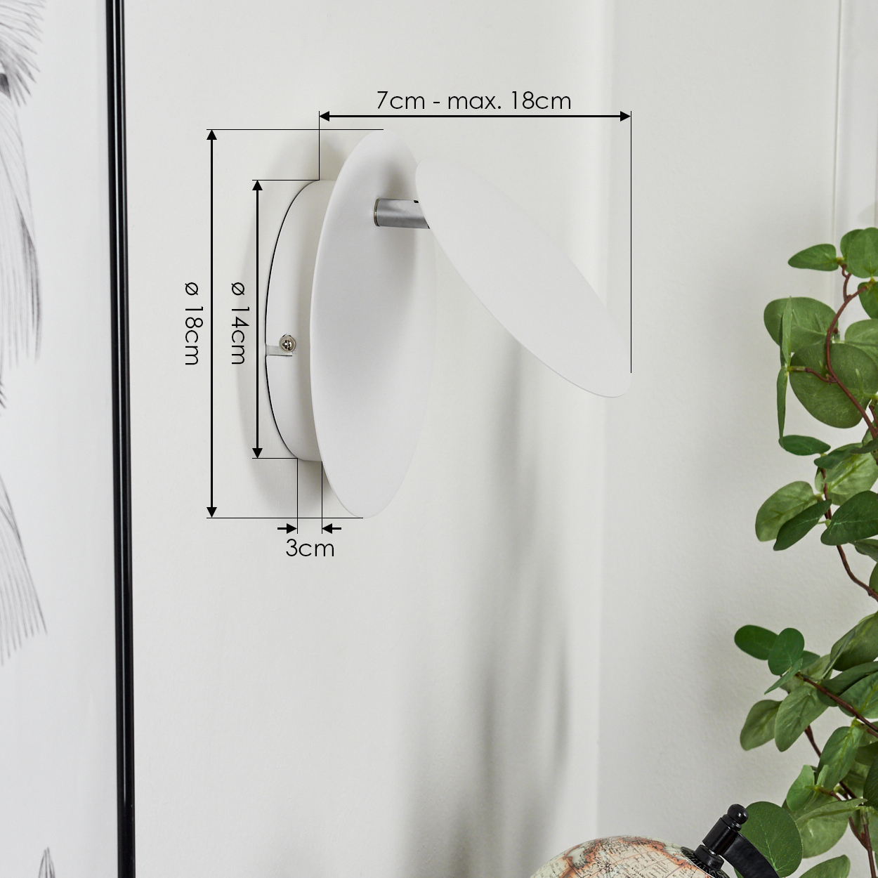 Eine weiße Wandleuchte mit zwei ovalen Formen. Die Abmessungen sind an der Wand angegeben. Rechts ist eine Pflanze zu sehen.