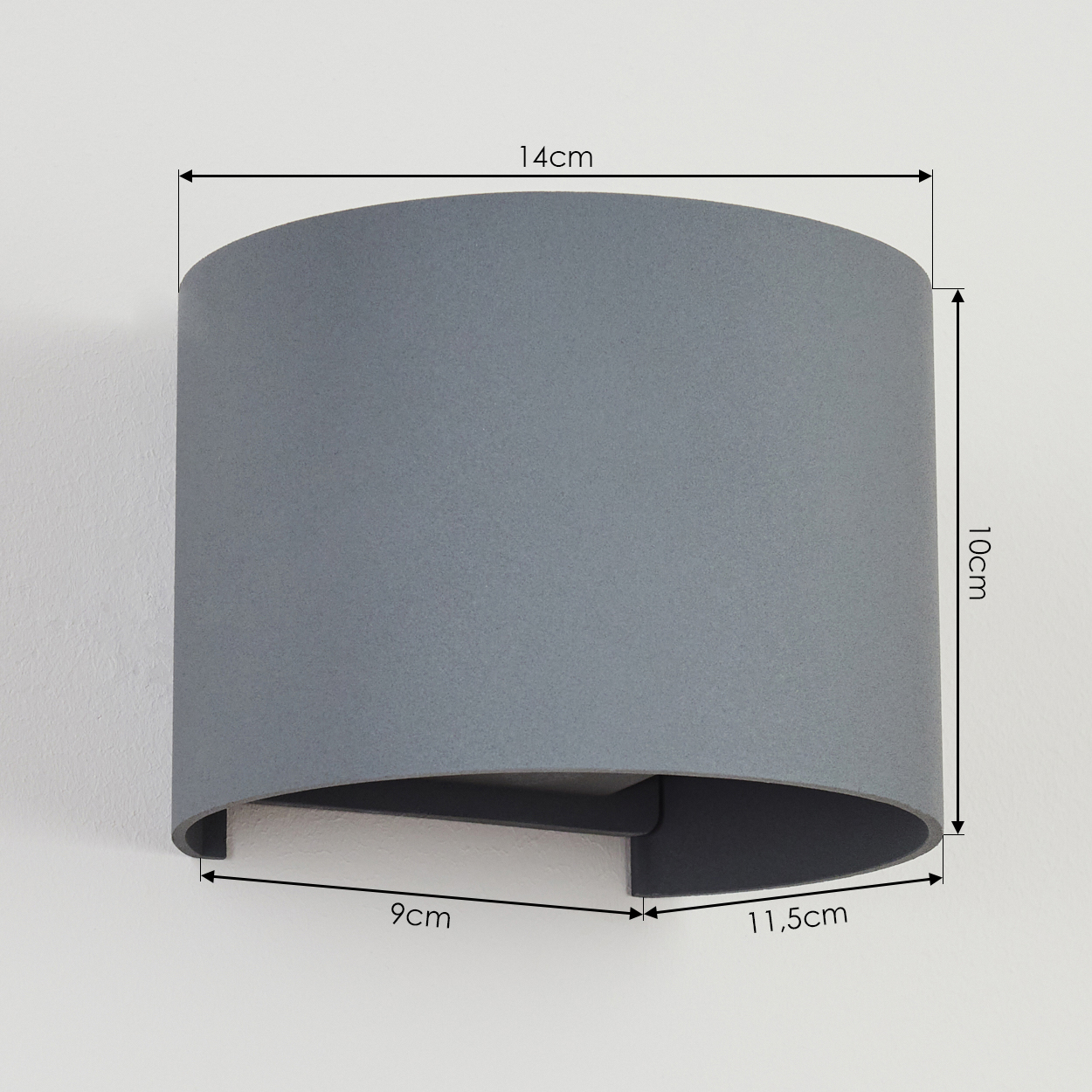 Ein grauer Lampenschirm an einer weißen Wand. Maße: 14 cm breit, 10 cm hoch, Boden 9 cm/11,5 cm.