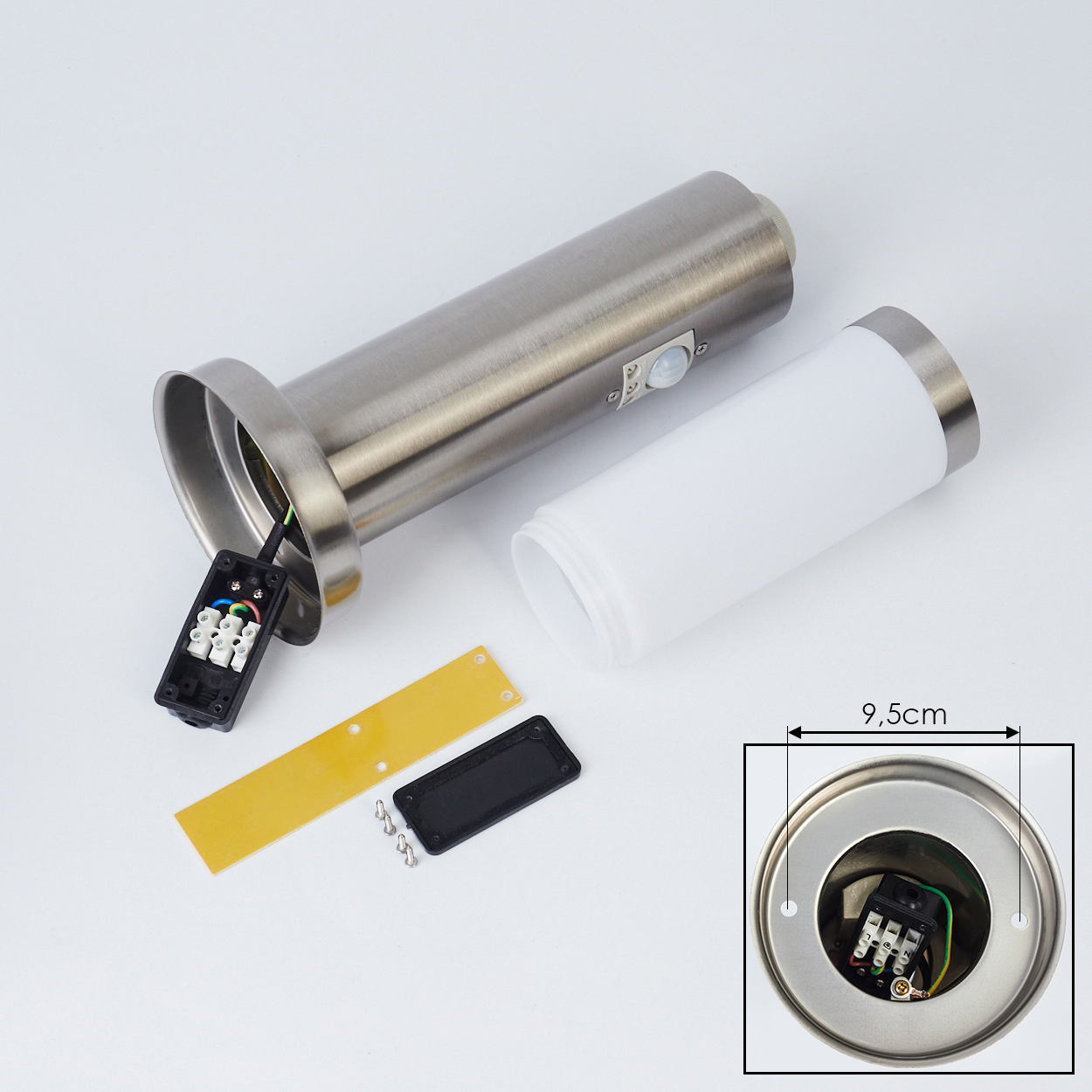 Zerlegte zylindrische Lampenteile. Edelstahlgehäuse, weißer Kunststoffdiffusor, schwarze und gelbe elektrische Komponenten und Schrauben.